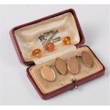 A pair of 9ct oval engine cufflinks, cased, together with a single 9ct collar stud (8.4g gross)