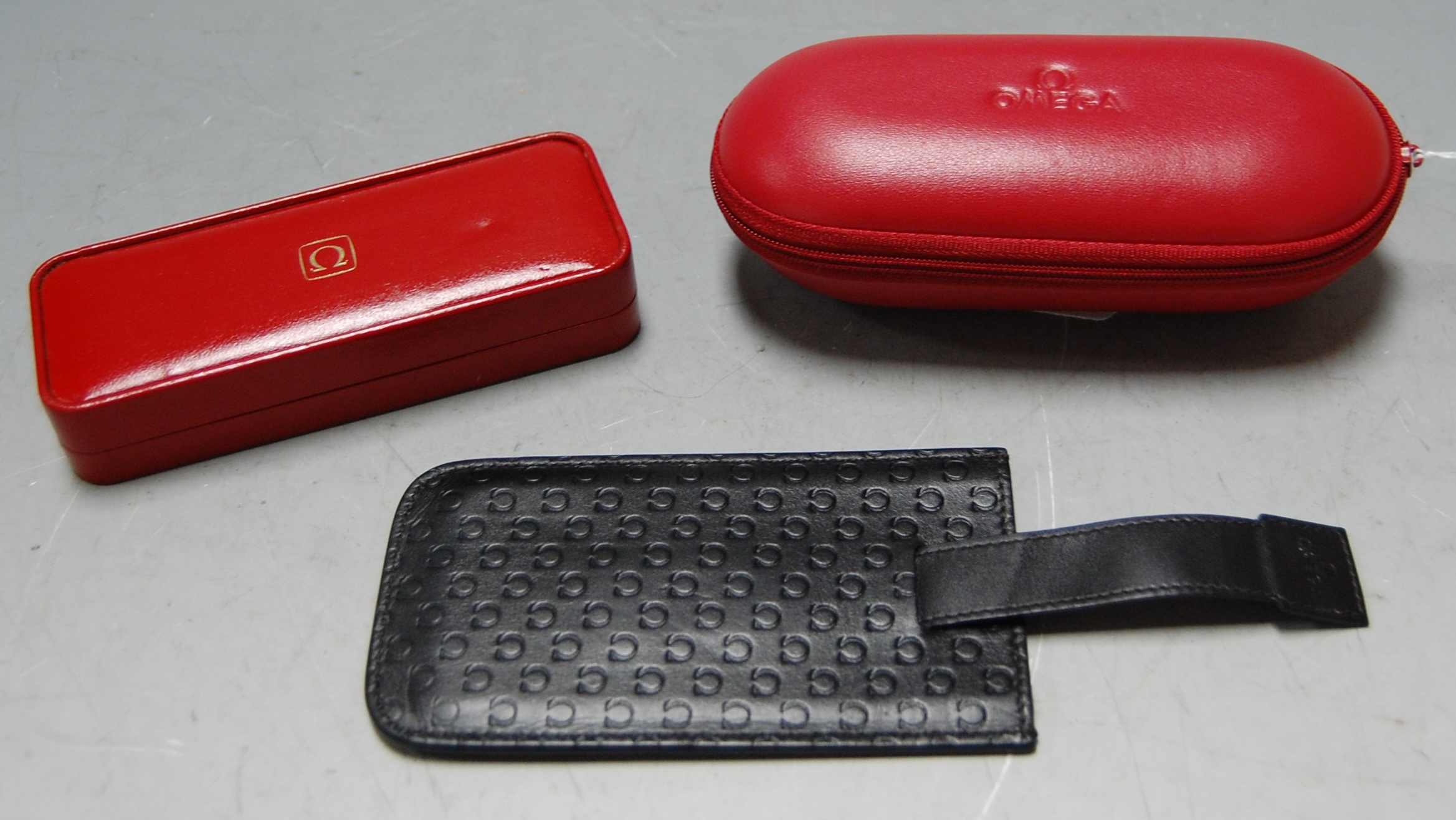 An Omega red leather watch case together with two other Omega leather pouches and an Omega watch