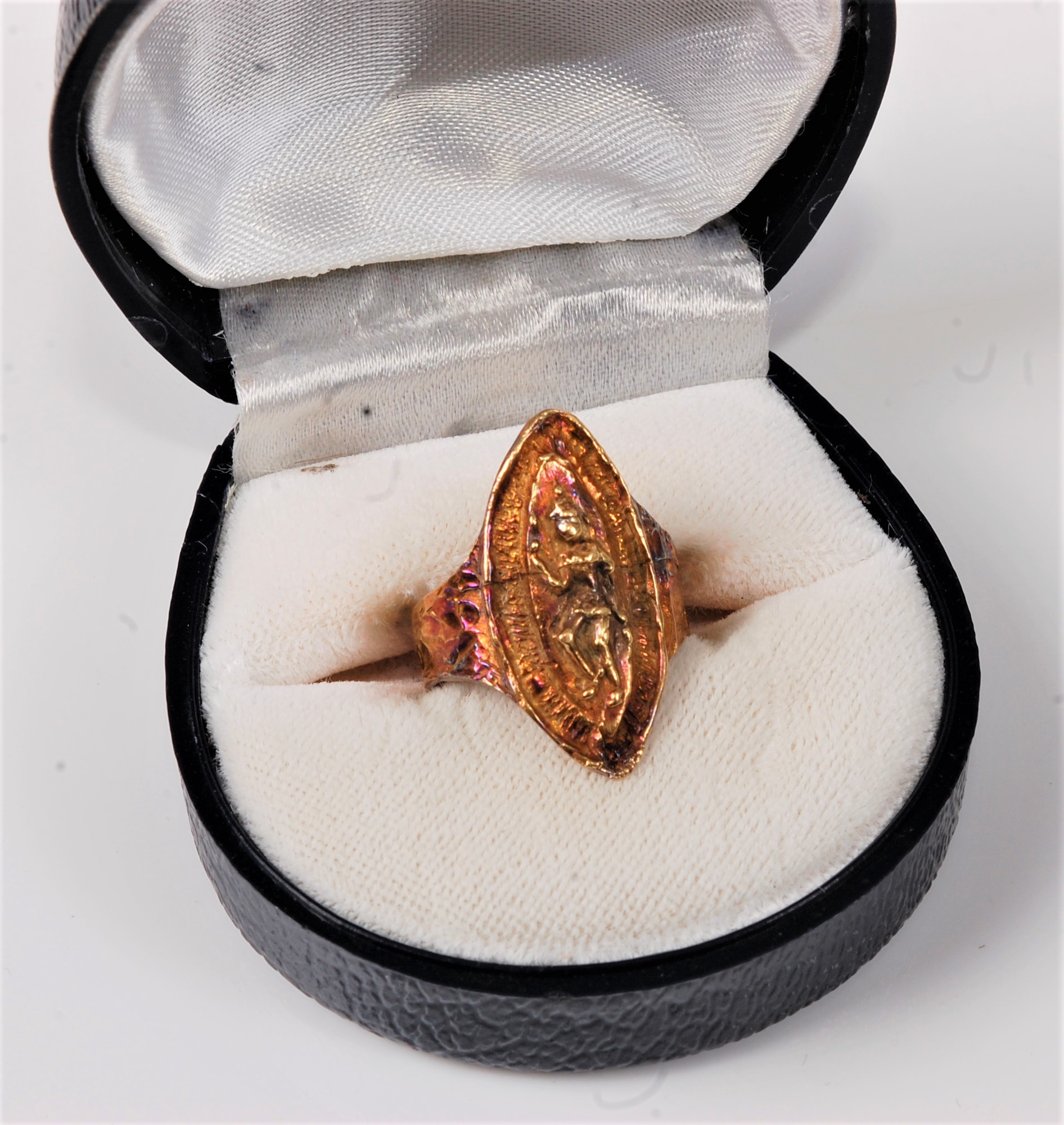 A marquise shaped ring, modelled with an Eastern figure, tapered shoulders and textured band stamped