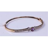 A 9ct amethyst and diamond hinged bangle, the oval amethyst set to the centre of a bow set with