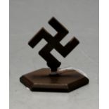 A bronzed desk weight in the form of a swastika on a hexagonal base