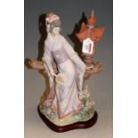 A Lladro porcelain figure of a Japanese Geisha wearing full robes and holding an ivory fan, numbered