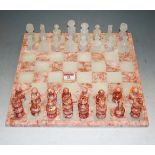 A modern onyx and marble chess set with board