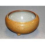 A Chinese stoneware crackle glazed bowl, decorated in a shade of ochre and raised on three dwarf