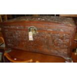 An early 20th century Indonesian relief carved camphor wood domed hinge top blanket box, having