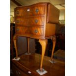 A reproduction mahogany and flame mahogany dropflap serpentine chest of three long drawers, w.55cm
