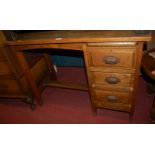 A small early 20th century oak single pedestal desk, having a dropflap end