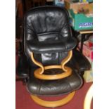 A Stressless black leather upholstered swivel armchair raised on layered plywood stand, together