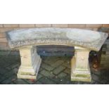 A reconstituted stone curved garden bench raised on end stepped pedestals, width 114cm, together