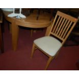 A contemporary light oak circular dining table with two matching slatback dining chairs, and a