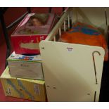 A vintage wooden dolls cot with a modern release doll and various clothing together with three boxed