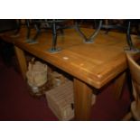 A contemporary light oak draw-leaf dining table having cleated ends and raised on square block