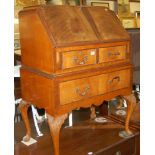 An early 20th century mahogany and flame mahogany slopefront writing bureau, having two short over