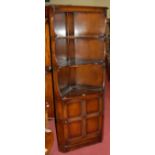 An Ercol dark elm freestanding corner cupboard, having panelled lower door