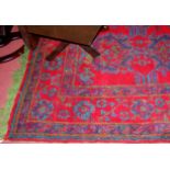 A Persian style red ground woollen rug by Chamberlain, King & Jones Ltd of Birmingham, having floral