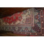 A Persian style machine-woven red ground rug, having multiple trailing borders, 325 x 234cm