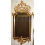 A contemporary gilt framed wall mirror, having a floral scroll surmount in the mid 18th century