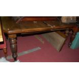 A late Victorian oak extending dining table, having wind-out action and two extra drop-in leaves,