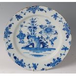 An 18th century English Delft charger, blue dash decorated with flowers and foliage (rim chips and