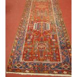 A Persian Heriz woollen hall runner , the red ground decorated with medallions and motifs within