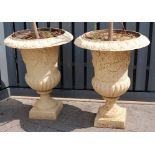 A pair of cast iron pedestal campagna urns , each having egg and dart top rims (one chipped), cherub