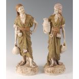A pair of Royal Dux Bohemia figures of water-carriers , modelled in standing poses and wearing
