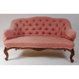 A Victorian rosewood framed salon settee, the whole re-upholstered in a buttonback pink silk