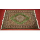 A Persian woollen green ground rug, the central field decorated with a lozenge medallion within
