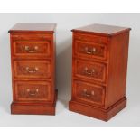 A pair of figured walnut and crossbanded three drawer bedside chests, having a brushing slide over