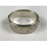 A silver hinged bangle with foliate engraving