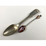 A Georgian silver old English pattern spoon together with a white metal and enamelled souvenir