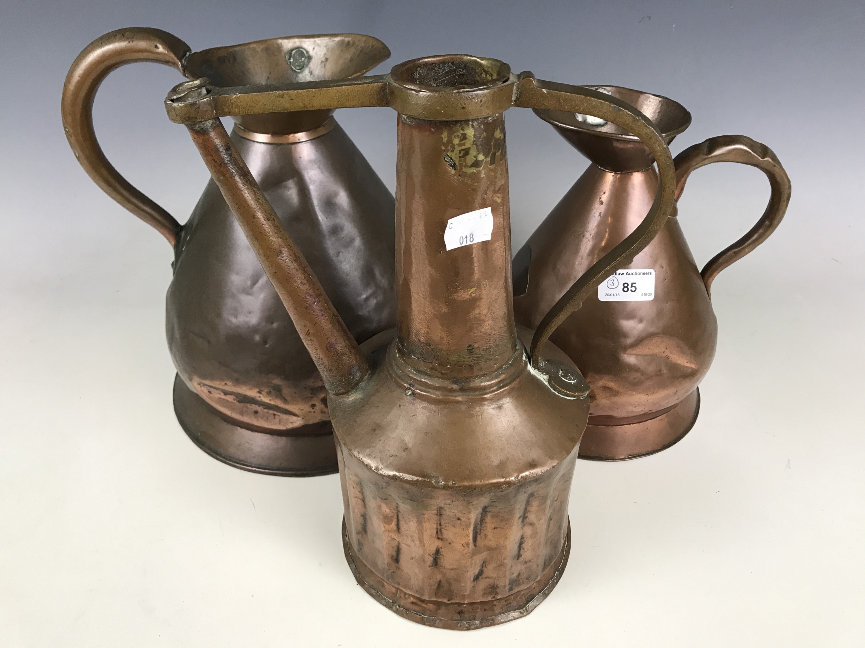 Two copper measuring jugs, one and two gallons respectively, together with a copper watering can