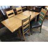 A contemporary light oak dining table with extra leaf and four dining chairs