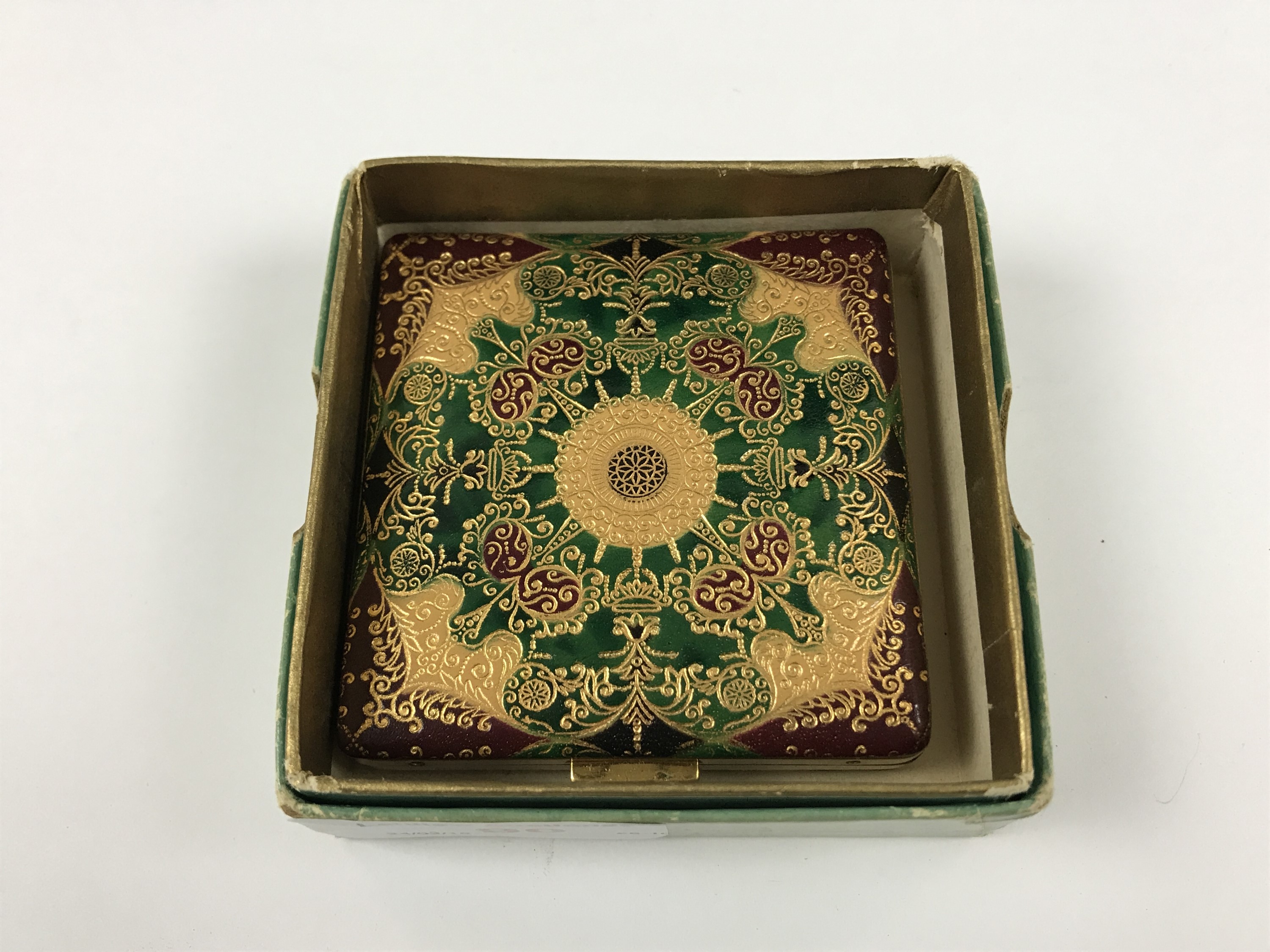 A vintage pressed-powder compact with tooled faux-leather cover, in original carton