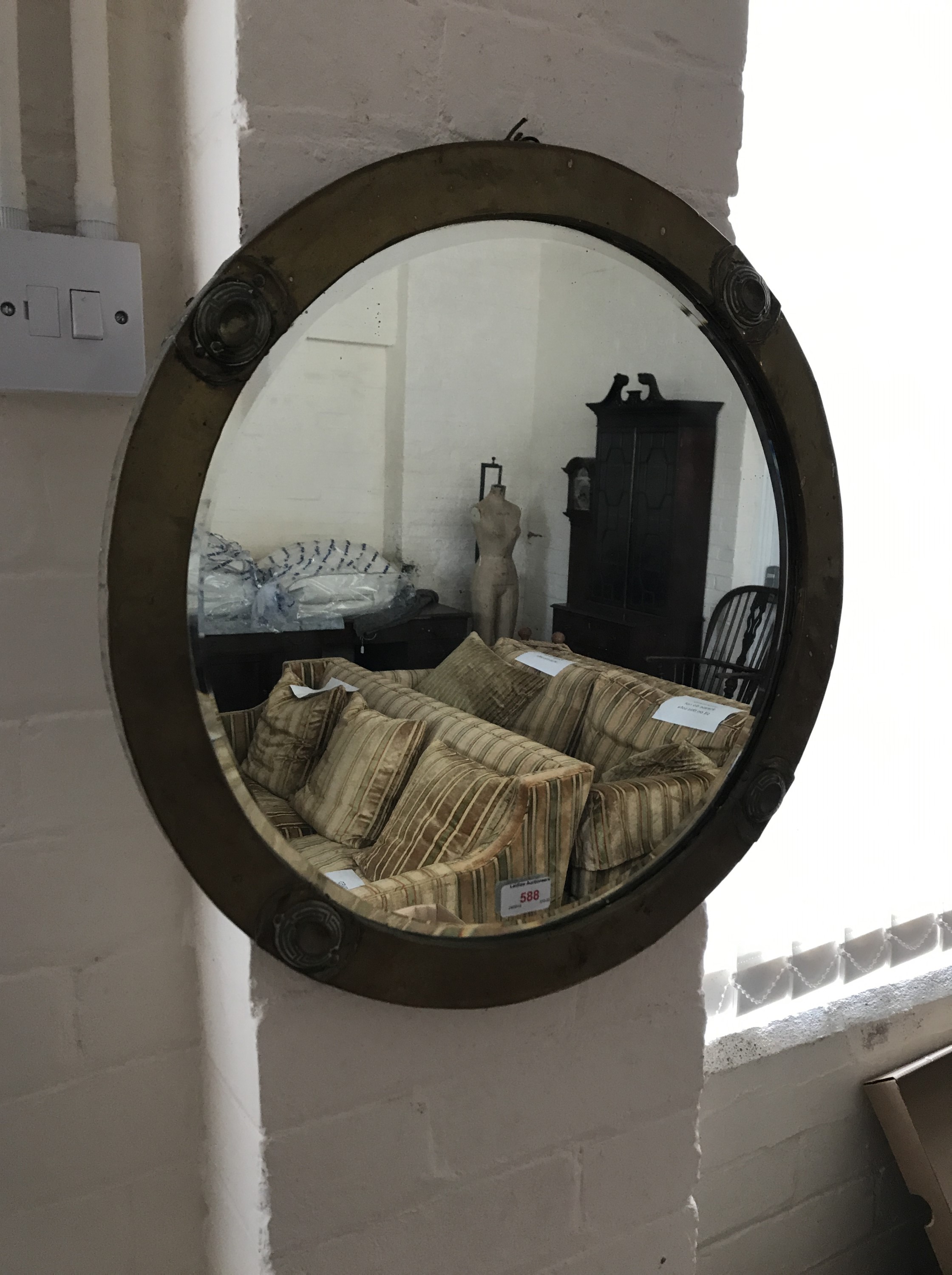 An early 20th Century brass framed circular wall mirror, having applied bosses to the four