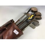 A vintage canvas and hide golf bag with sundry hickory-shafted clubs by Saint Andrews, Seascale,