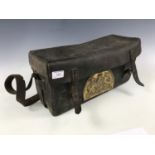 An antique leather satchel with applied brass Royal Arms plaque