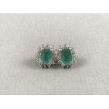 A pair of contemporary emerald and diamond stud earrings, in a flower head cluster arrangement,