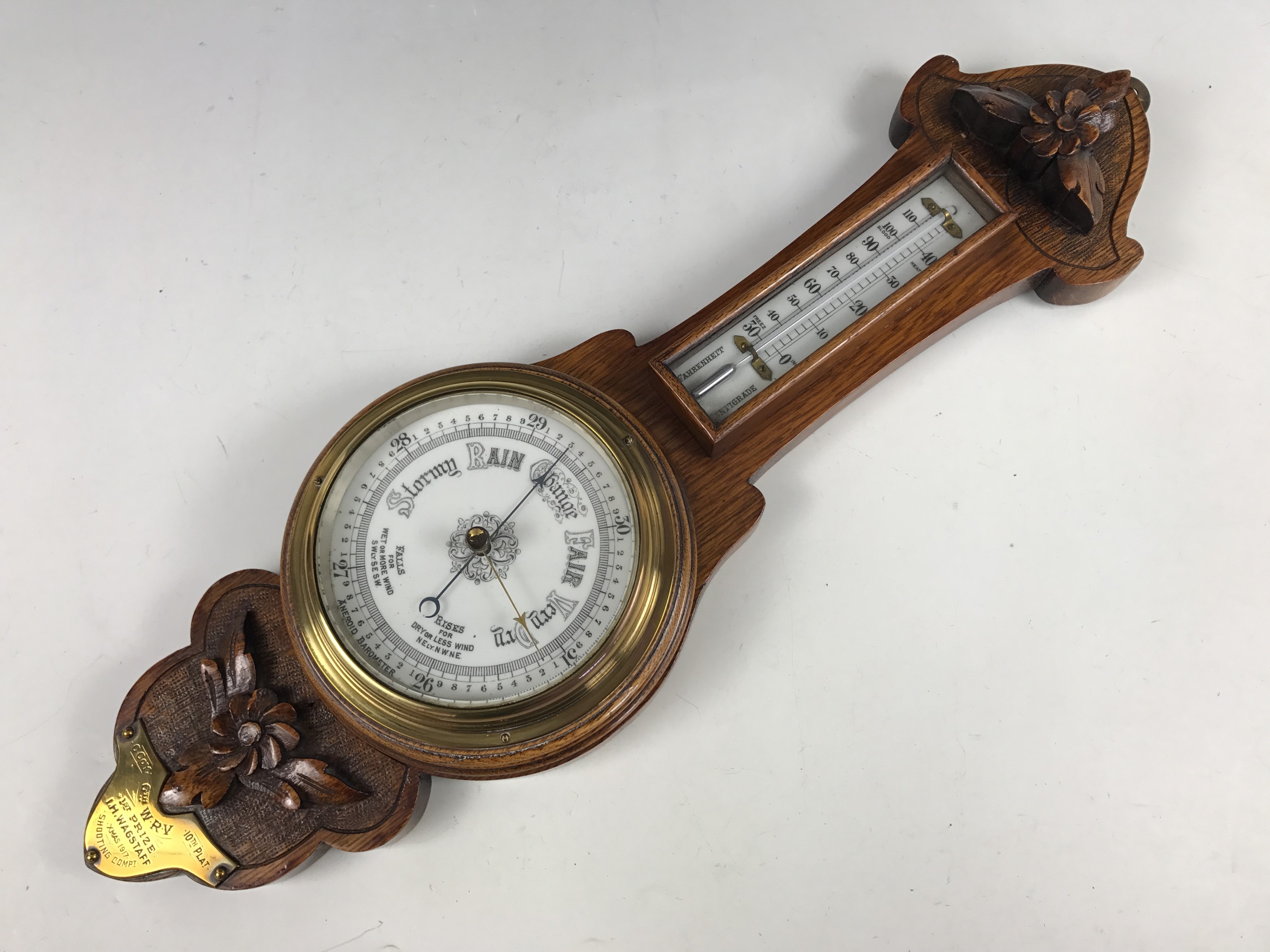 An early 20th Century carved oak banjo barometer bearing a brass plaque with engraved presentation