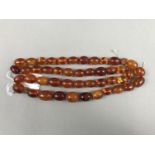 A single strand necklace of oval amber beads, beads approximately 20 x 15 mm and smaller, 80 cm,