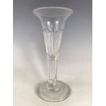 A late Georgian wine glass, of drawn trumpet form, the bowl and stem faceted, the stem having a tear