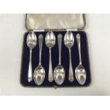 A cased set of six George V silver tea spoons, having cusped terminals bearing a golf club device,