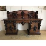A flamboyant Victorian carved mahogany pedestal sideboard, the back faced with pair of high-relief