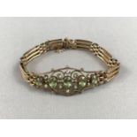 A Belle Epoch peridot, pearl and precious yellow-metal bracelet, having an openwork face centrally