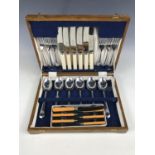 An oak canteen of cutlery together with boxed butter knives