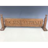 A carved wooden The Craftsman advertising sign with thistle terminals