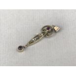 An Edwardian almandine garnet and seed pearl openwork pendant, of slender scrolling form, stamped