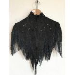 A late Victorian jet-beaded chevron capelet with cap sleeves, having hand-applied decoration in