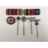 A group of German Third Reich insignia including stick pins and a party badge, together with two