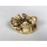 A Meiji Japanese large marine ivory katabori netsuke depicting characters sat serving a Hotei-like